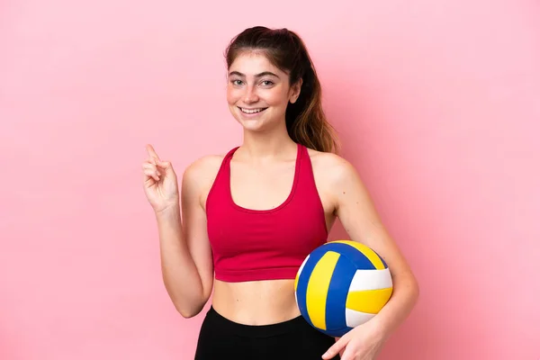 若いです白人女性は 製品を提示する側を指してピンクの背景に孤立バレーボールをプレイ — ストック写真