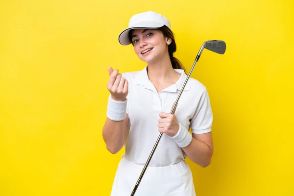 若い白人女性が黄色の背景に孤立したゴルフをしてお金のジェスチャーをする — ストック写真