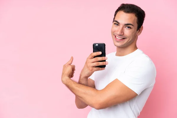 Νεαρός Καυκάσιος Άνδρας Απομονωμένος Ροζ Φόντο Χρησιμοποιώντας Κινητό Τηλέφωνο Και — Φωτογραφία Αρχείου