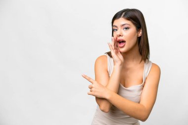 Young Russian woman over isolated white background pointing to the side to present a product and whispering something