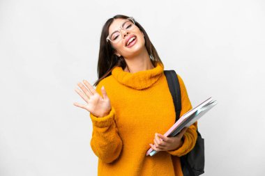 İzole edilmiş beyaz arka planda genç bir bayan mutlu bir ifadeyle selamlıyor.