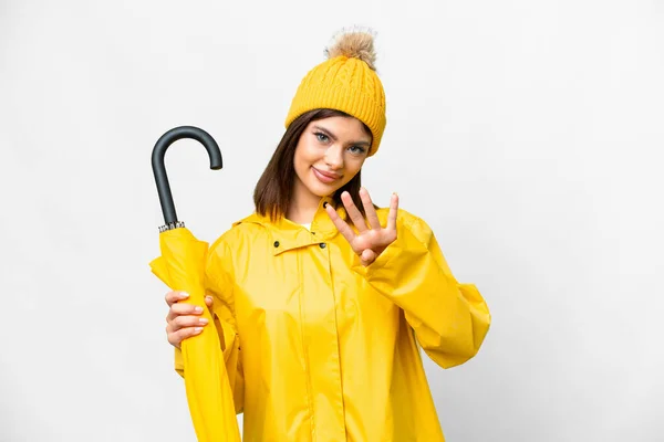 Young Russian woman with rainproof coat and umbrella over isolated white background happy and counting four with fingers