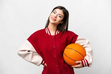 Genç Rus kadın izole edilmiş beyaz arka planda basketbol oynuyor. Kolları kalçasında ve gülümsüyor.
