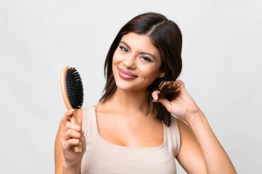 Young Russian woman over isolated white background with hair comb