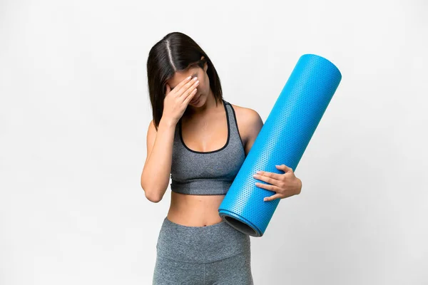 年轻的女运动员一边去上瑜伽课 一边拿着垫子盖住孤独的白色背景 脸上带着疲惫和病态的表情 — 图库照片