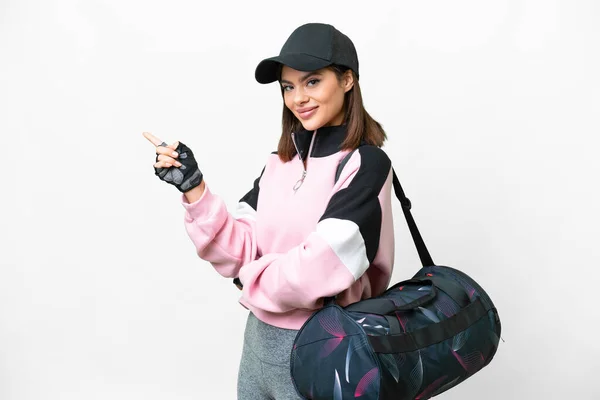 Young sport woman with sport bag over isolated white background pointing finger to the side