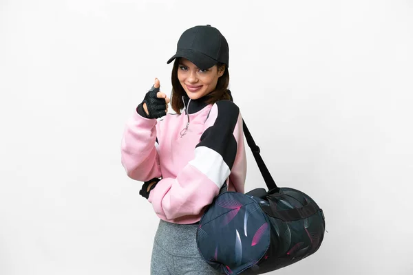 Young sport woman with sport bag over isolated white background points finger at you with a confident expression