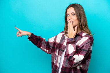 Mavi arka planda izole edilmiş beyaz bir kadın, sürpriz bir ifadeyle işaret ederken...