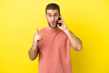 Handsome blonde man using mobile phone over isolated background intending to realizes the solution while lifting a finger up