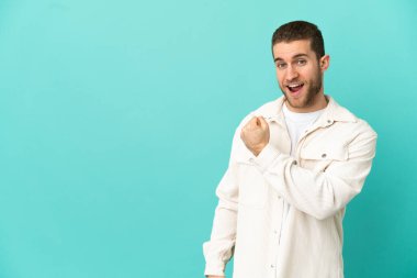 Handsome blonde man over isolated blue background celebrating a victory