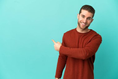 İzole edilmiş mavi arka planı olan yakışıklı sarışın adam.
