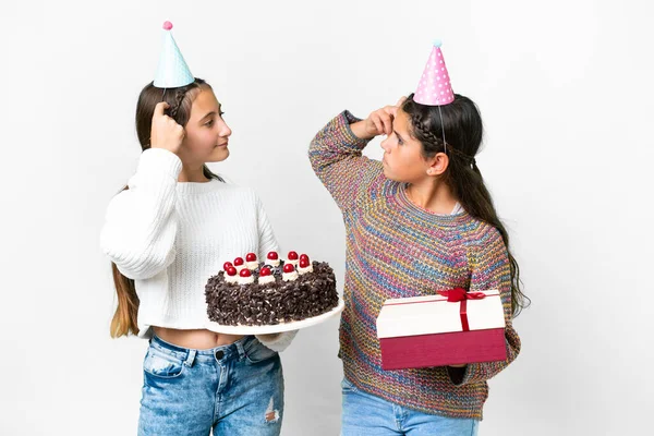 朋友们手里拿着礼物和生日蛋糕的女孩们 在孤独的白色背景下一边抓着头一边怀疑 — 图库照片