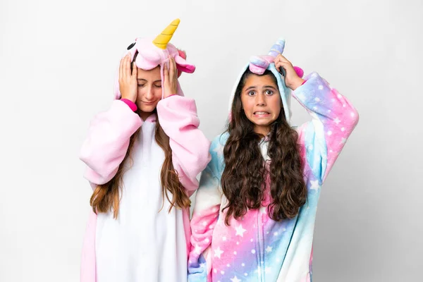 Stock image Friends girls with unicorn pajamas over isolated white background takes hands on head because has migraine