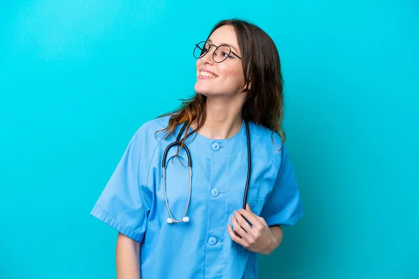 Молода Жінка Хірург Ізольована Синьому Фоні Дивлячись Бік Посміхаючись — стокове фото
