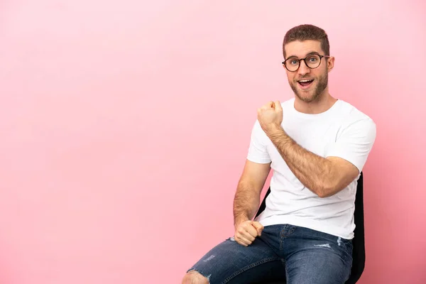 Young Man Sitting Chair Isolated Pink Background Celebrating Victory — Stock fotografie