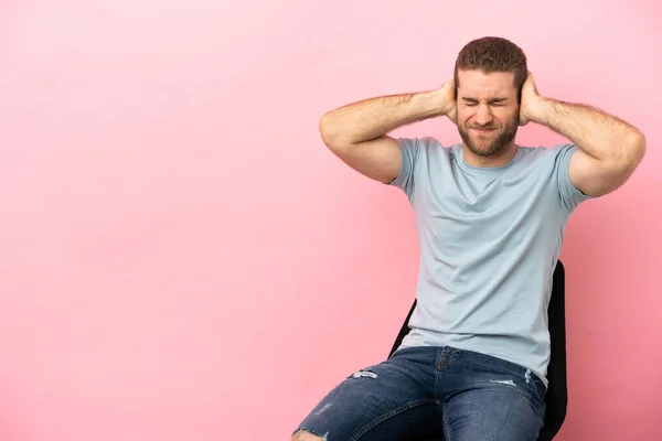 Young Man Sitting Chair Isolated Pink Background Frustrated Covering Ears — Stock fotografie