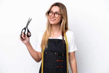 Kafkasyalı genç terzi kadın beyaz arka planda izole edilmiş bir şekilde yukarı bakarken bir fikir düşünüyor.