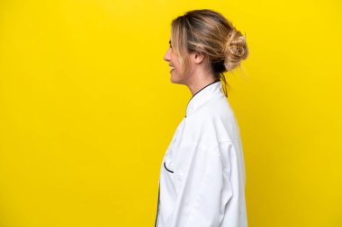 Uruguaylı aşçı kadın sarı arka planda izole edilmiş. Yan yana gülüyor.