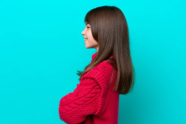 Mavi arka planda, yanal pozisyonda izole edilmiş küçük beyaz kız.