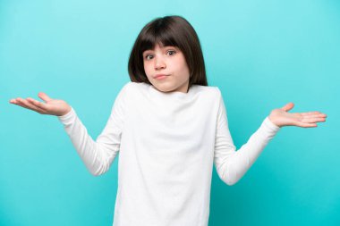 Little caucasian girl isolated on blue background making doubts gesture