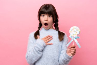 Küçük beyaz kız elinde lolipop tutarken şaşırdı ve şaşırdı.