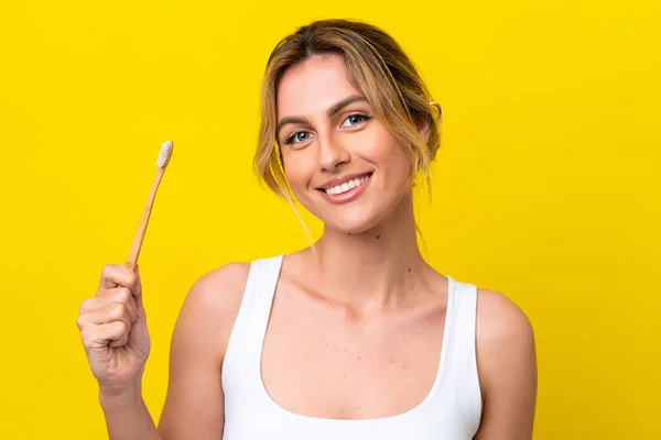 Młoda Urugwajska Kobieta Myjąca Zęby Odizolowana Żółtym Tle Uśmiechnięta — Zdjęcie stockowe