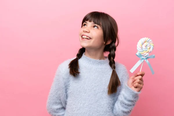 Little Caucasian Girl Holding Lollipop Thinking Idea While Looking — Stockfoto