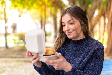 Genç ve güzel Romen kadın elinde hamburgerle