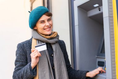 Açık havada elinde kredi kartı olan esmer bir kadın.