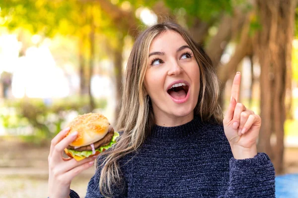 Młoda Ładna Rumuńska Kobieta Trzymając Hamburgera Świeżym Powietrzu Zamiarem Realizacji — Zdjęcie stockowe
