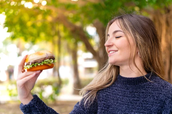 Młoda Ładna Rumuńska Kobieta Trzyma Hamburgera Świeżym Powietrzu Szczęśliwą Ekspresją — Zdjęcie stockowe