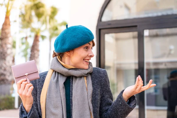 Stock image Brunette woman holding a wallet at outdoors with surprise facial expression