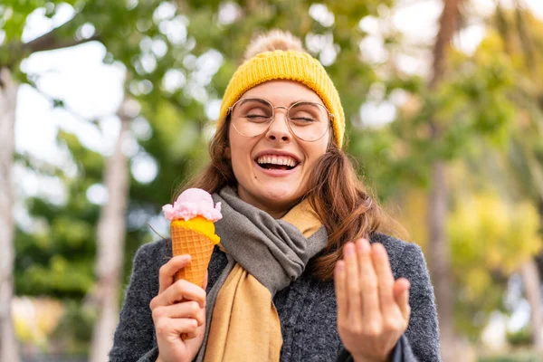 Stock image Brunette woman with a cornet ice cream at outdoors inviting to come with hand. Happy that you came