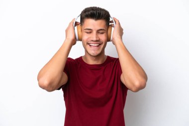 Beyaz arka planda izole edilmiş genç beyaz adam müzik dinliyor.