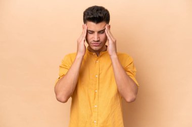 Beyazlı genç bir adam bej arka planda izole edilmiş baş ağrısı var.