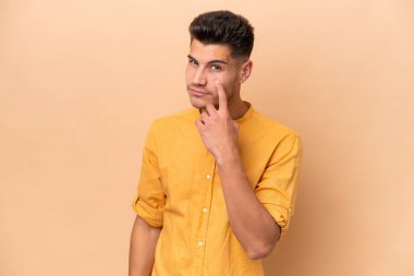 Beyazlı genç bir adam bej arka planda izole edilmiş.