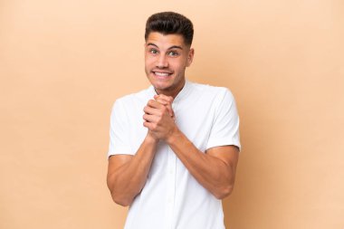 Beyazlı genç bir adam bej arka planda izole edilmiş gülüyor.