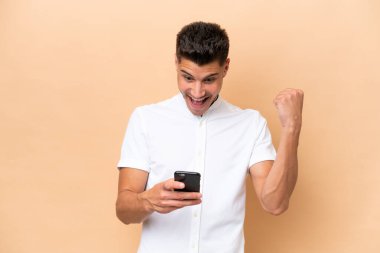 Beyazlı genç bir adam bej arka planda izole edildi. Şaşırdı ve bir mesaj gönderiyor.