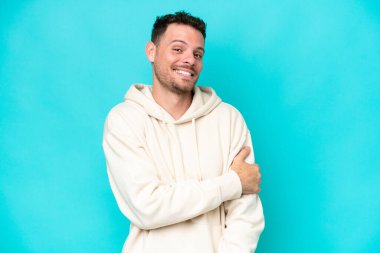 Genç beyaz yakışıklı adam mavi arka planda izole edilmiş gülüyor.