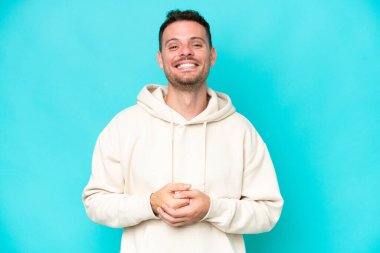 Genç beyaz yakışıklı adam mavi arka planda izole edilmiş gülüyor.