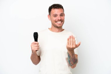 Beyaz arka planda izole edilmiş bir mikrofonu kaldıran beyaz tenli genç şarkıcı, bizimle gelmesi için davet ediyor. Gelmene sevindim.