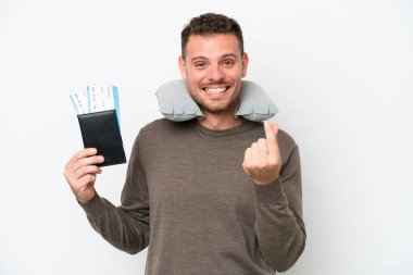 Young caucasian man holding a passport isolated on white background making money gesture