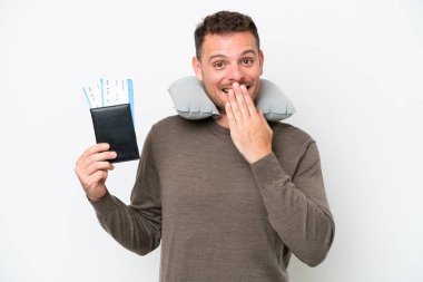 Beyaz arka planda izole edilmiş pasaportu olan genç beyaz bir adam mutlu ve ağzı kapalı gülümsüyor.