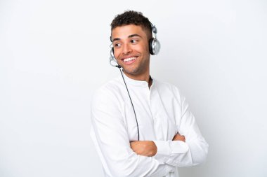 Telemarketer Brazilian man working with a headset isolated on white background with arms crossed and happy