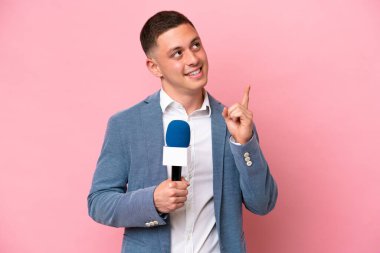 Genç Brezilyalı sunucu, pembe arka planda izole edilmiş. Harika bir fikre işaret ediyor.