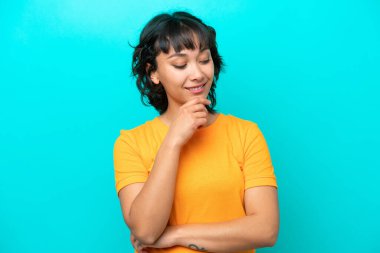 Young Argentinian woman isolated on blue background looking to the side and smiling