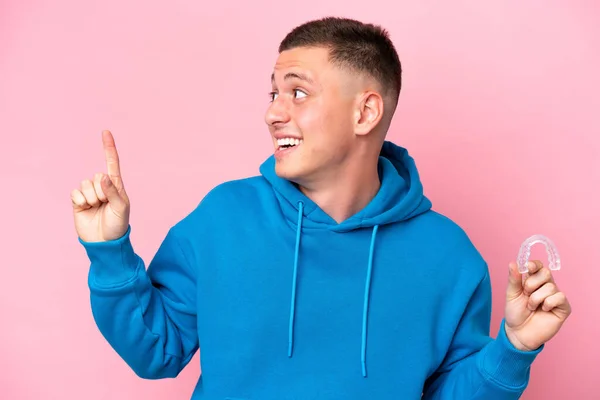 Young Brazilian Man Holding Invisible Braces Isolated Pink Background Intending — Stock Photo, Image