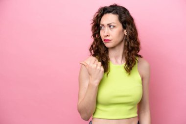 Pembe arka planda izole edilmiş genç beyaz kadın mutsuzdu ve yan tarafı gösteriyordu.