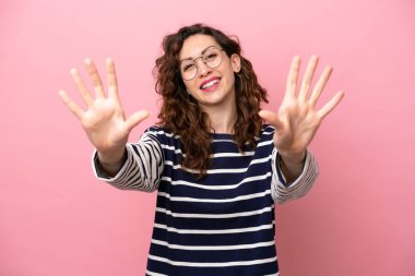 Pembe arka planda izole edilmiş beyaz kadın parmaklarıyla 10 'a kadar sayıyor.