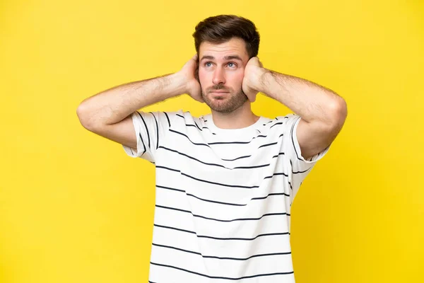 若い白人男性は黄色の背景に不満とカバー耳に隔離 — ストック写真